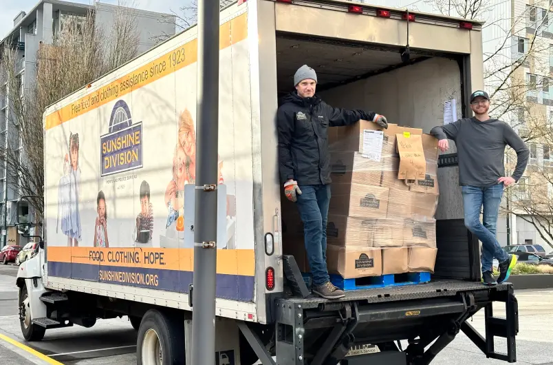 Sunshine Division Delivery Crew Standing in the Back of a Box Truck with Arms Resting on Food Boxes