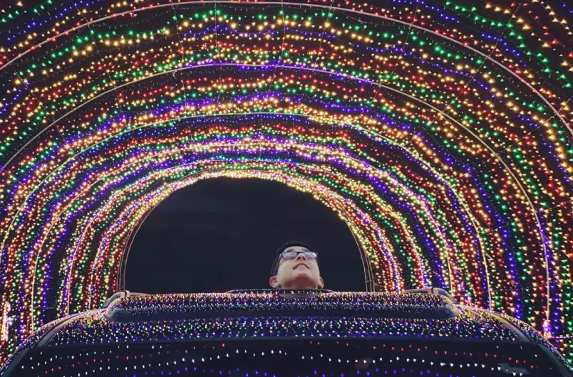 Young Kid Looks Up Through Sun Roof of Vehicle While Driving Through the Holiday Lights Tunnel at Winter Wonderland